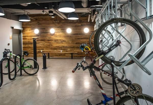 Local à vélos moderne avec système de rangement mural et éclairage industriel, offrant un espace organisé et sécurisé pour les cyclistes.