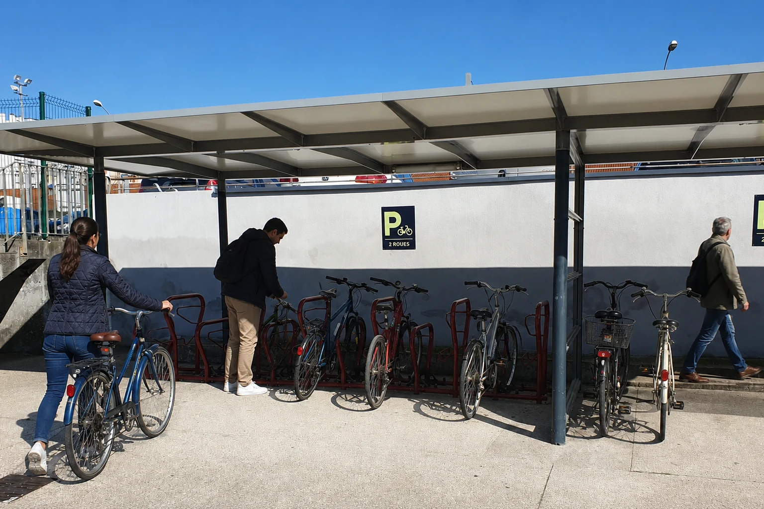 Vraie photographie des racks et de l’abri vélo à la sortie Sud de la gare de Clermont-Ferrand, retouchée avec de nouveaux cyclistes