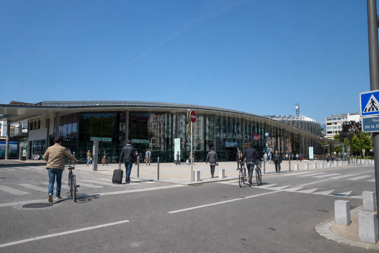 Vue extérieure réelle de la gare d’Annecy, retouchée avec de nouveaux voyageurs et vélos pour servir de repère