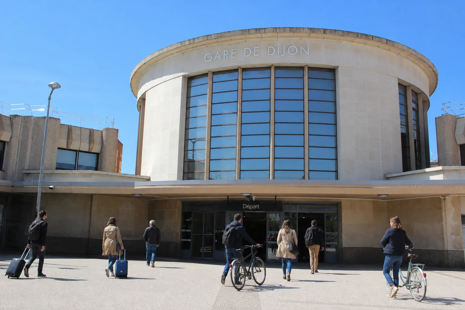 Façade réelle de la gare de Dijon-Ville retouchée avec des voyageurs entièrement nouveaux et des vélos recolorés et déplacés